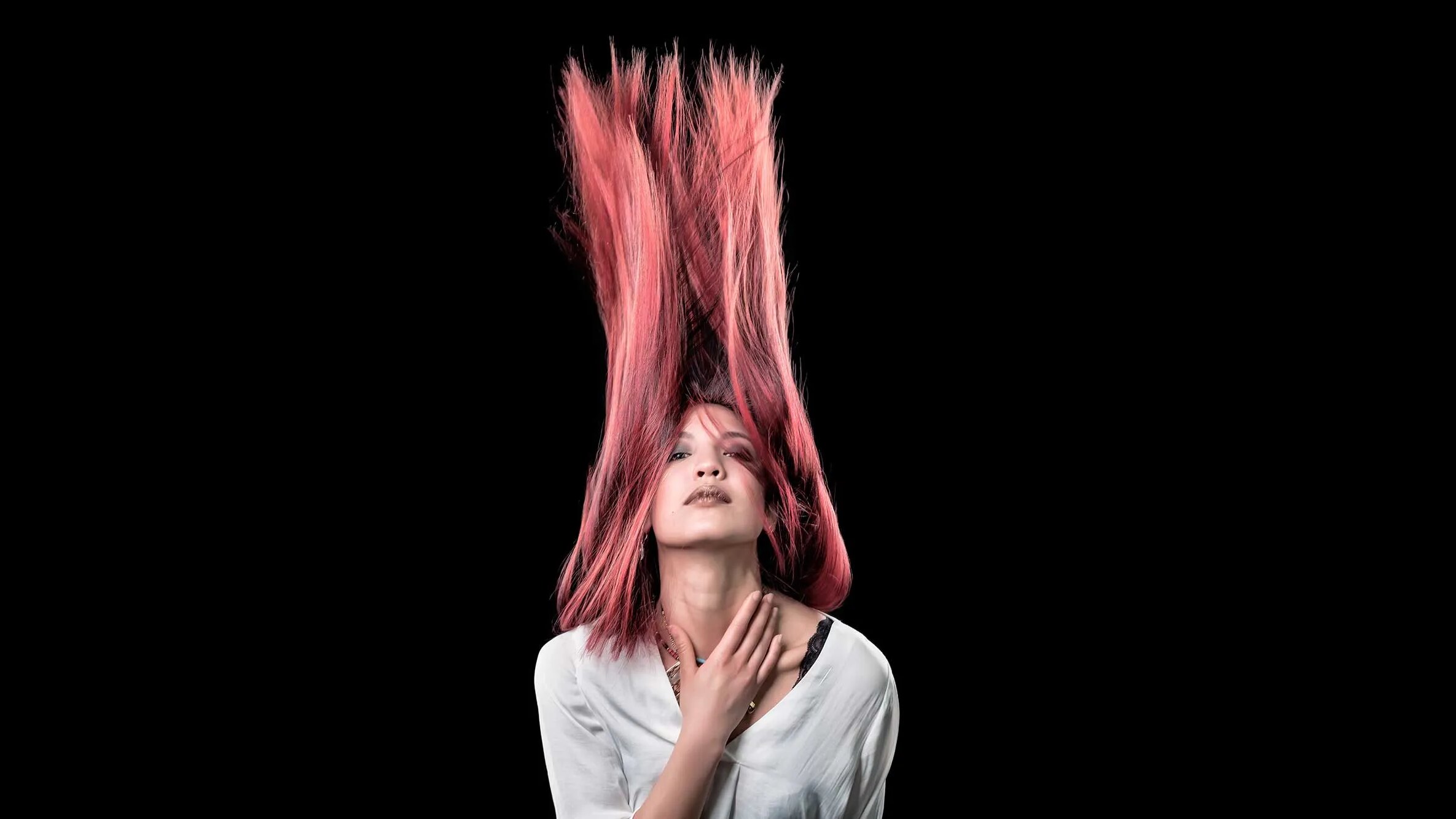 Sul nero si vede solo lei: il flash le ferma i capelli rosa dritti verso l'alto. La forma che prendono la scegli tu.
